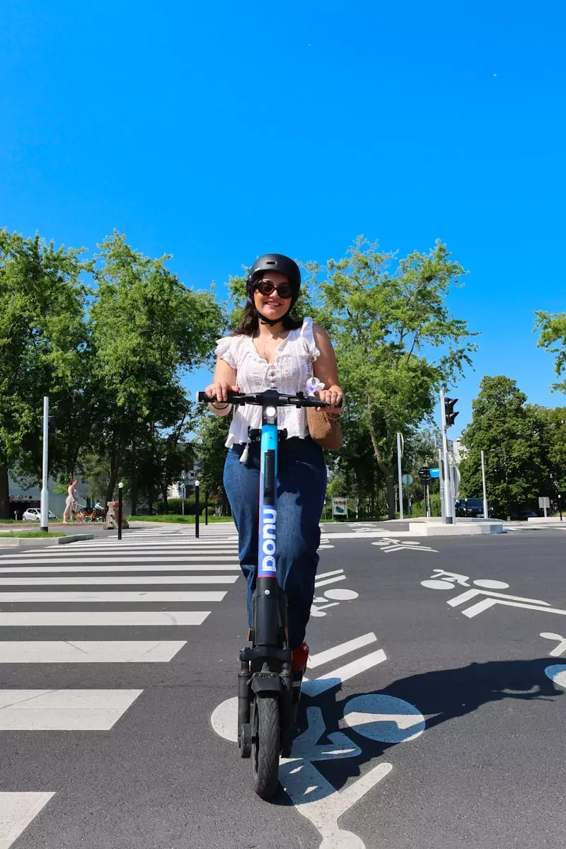 A woman riding a scooter across a street